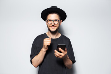 Studio portrait of happiness guy wearing hat using smartphone on white.