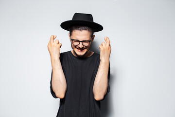 Portrait of happiness man crosses fingers with closed eyes on grey background.