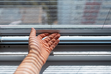 Close-up of male hand trying to open the modern mosquito net on plastic window.