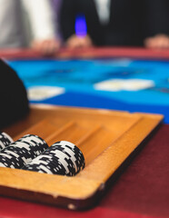 Fototapeta premium Poker table view with a pack of cards, tokens, alcohol drinks, dollar money and group of gambling rich wealthy people playing poker in casino, with croupier