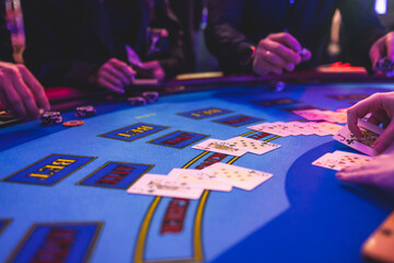 Poker table view with a pack of cards, tokens, alcohol drinks, dollar money and group of gambling rich wealthy people playing poker in casino, with croupier