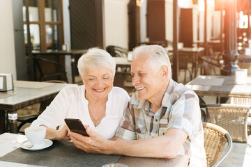 Senior couple using mobile phone in a cafe