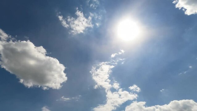 Bright sunny summer day sky with light clouds. Soft clouds covering sun from time to time. Timelapse. View from below.