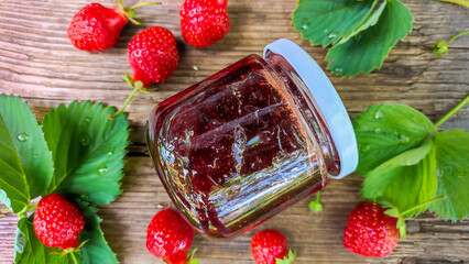 Strawberry jam in a glass jar on the table. - 511593871