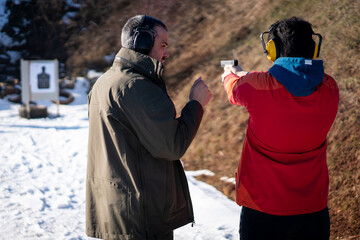 Trainer helping young person to aim with handgun at combat training. High quality photo