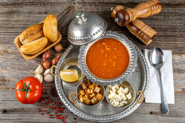 Delicious chicken soup with tomatoes  and some vegetables served in a cupper bowl served with bread.