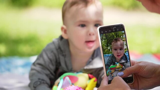 Mother wants to take photos of her son. Little boy wants to take the phone ignoring toys. Blurred backdrop.