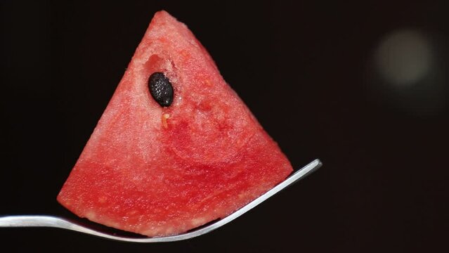 taking a piece of watermelon by spoon on dark background