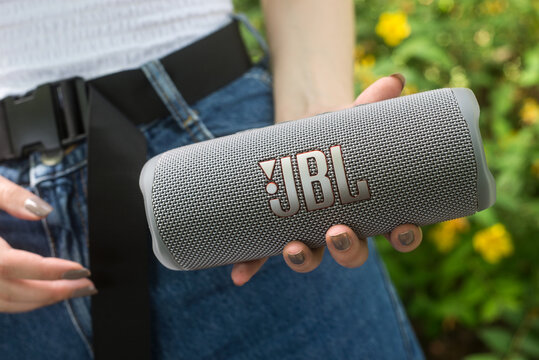 Mulhouse - France - 16 June 2022 - Closeup of grey portable JBL subwoofer speaker in hands of young woman standing in a public garden