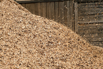 Large heaps of wood chips after pruning of trees and shrubs at the end of the winter season.