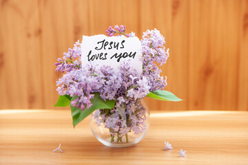 Jesus loves you - card with calligraphy lettering and purple lilac flowers, christian motivation phrase