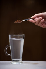 hand with small coffee spoon in cup with very hot water, breakfast concept