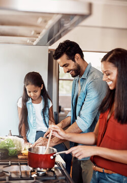 Time to cook, time to bond. Shot of a happy young family preparing a meal in the kitchen together at home.