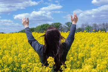 Girl with raised hands. Prayer. Praise God, Jesus. Yellow rapeseed field. Summer. Happy woman - obrazy, fototapety, plakaty
