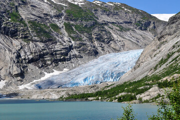 The huge Jostedalsbreen glacier in the middle of the rocky mountains above a lake in Norway