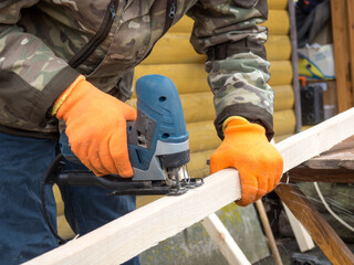 Working with power tools. man sawing a board with a jigsaw