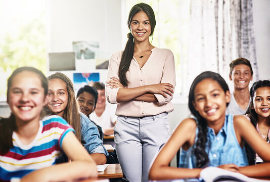 Their favourite class with their favourite teacher. Portrait of an attractive young teacher standing with her arms folded in a classroom.