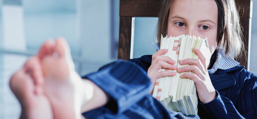 I will be rich! Young business girl sniffing the stacks of money in the office. Motivation and work concept. Horizontal image. Selective focus on eyes.