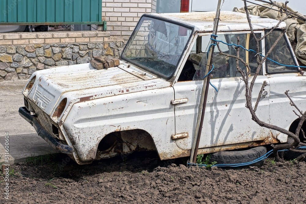 Wall mural one old disassembled white car stands on the ground on the street