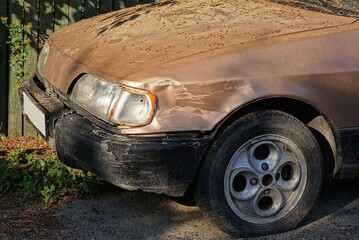 part of an old brown car after an accident with a dented metal fender over the wheel and a broken...