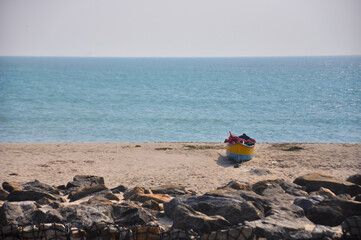 Blue and yellow fishing boat on a sandy beach overlooking the Indian Ocean at Arichal Munai, Dhanushkodi, Tamil Nadu, India