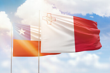 Sunny blue sky and flags of malta and chile
