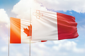 Sunny blue sky and flags of malta and canada