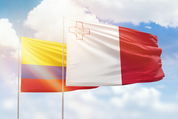 Sunny blue sky and flags of malta and colombia