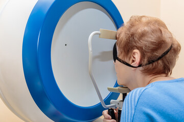 An adult girl at an ophthalmologist's appointment checks her eyesight on a special apparatus....