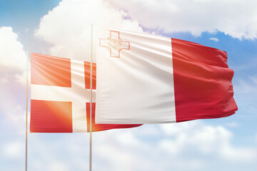 Sunny blue sky and flags of malta and denmark