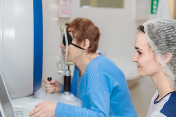 Obraz premium A girl optometrist examines the eyes of a patient using special modern equipment
