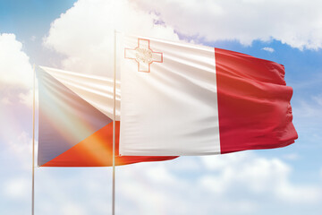 Sunny blue sky and flags of malta and czechia