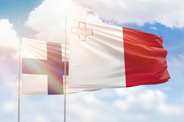 Sunny blue sky and flags of malta and finland