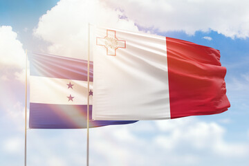 Sunny blue sky and flags of malta and honduras