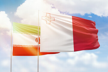 Sunny blue sky and flags of malta and iran