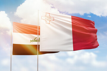 Sunny blue sky and flags of malta and iraq