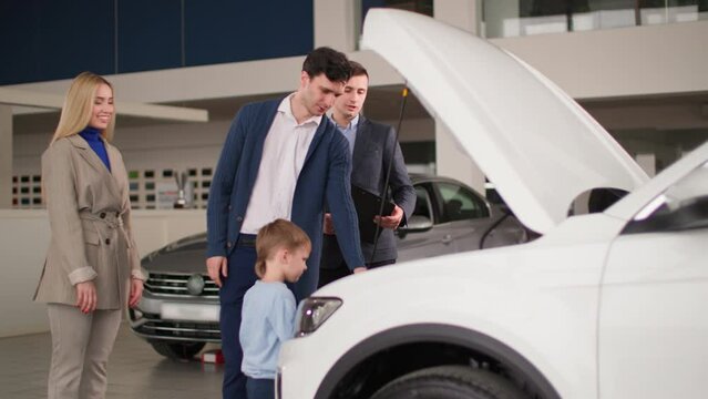 auto business, young husband with wife and son choose a new automobile, consult with a manager in a car dealership