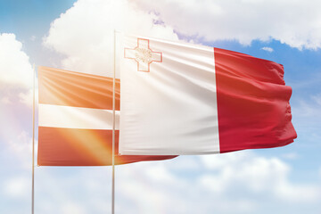 Sunny blue sky and flags of malta and latvia
