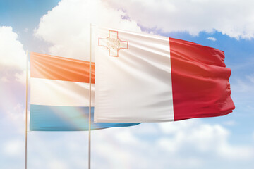 Sunny blue sky and flags of malta and luxembourg