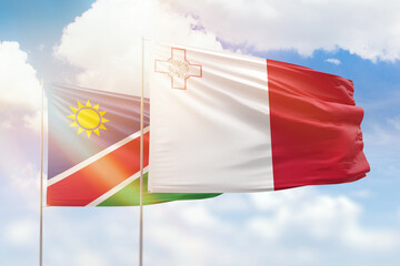 Sunny blue sky and flags of malta and namibia
