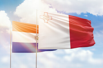 Sunny blue sky and flags of malta and paraguay
