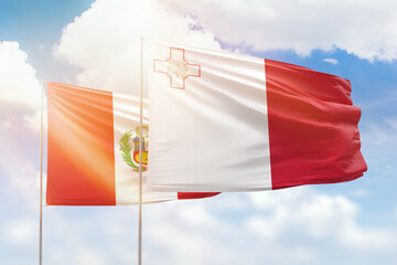 Sunny blue sky and flags of malta and peru