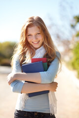 Fototapeta premium She loves her books. Portrait of a young girl holding her school books close to her chest.