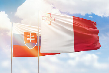 Sunny blue sky and flags of malta and slovakia