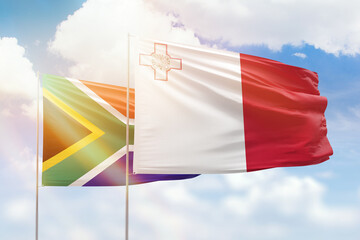 Sunny blue sky and flags of malta and south africa
