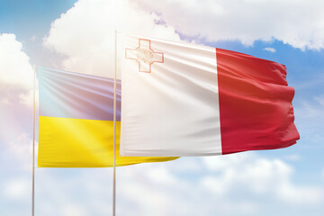 Sunny blue sky and flags of malta and ukraine