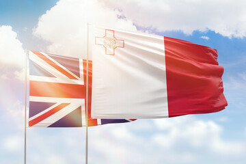 Sunny blue sky and flags of malta and united kingdom