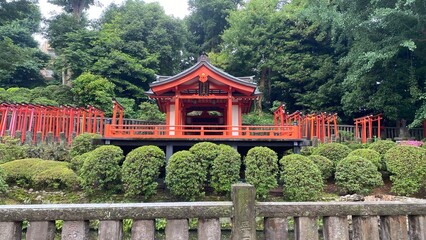 Early morning “Nezu” shrine in the downtown Tokyo, the red paint pagodas floating above the zen garden pond.  Year 2022 June 18th - obrazy, fototapety, plakaty