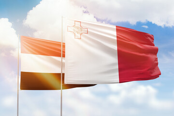 Sunny blue sky and flags of malta and yemen