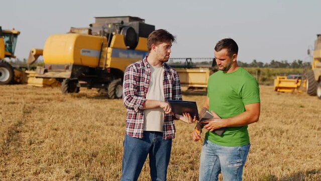 Farmer, logistics agent sign agreement on grain supply, shake hands in wheat field near harvesters. Agronomist discuss agriculture business contract. Rancher, landlord negotiate with handshake.